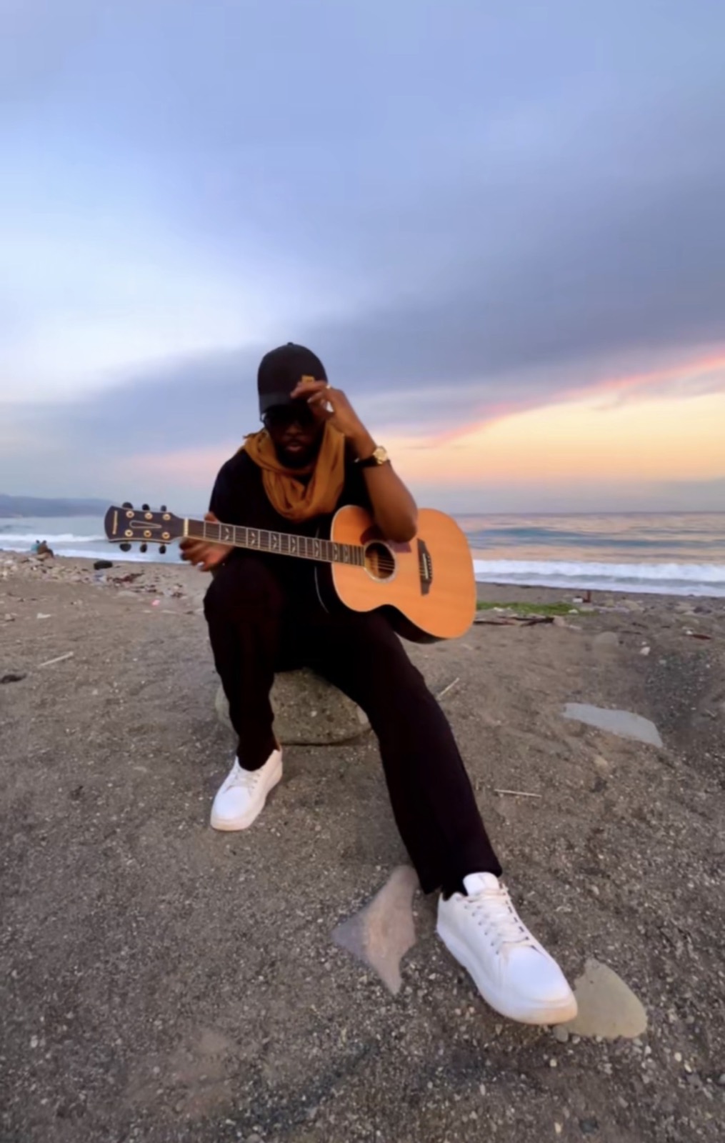 Kevin Downswell with an acoustic guitar on a Jamaican shoreline at first light