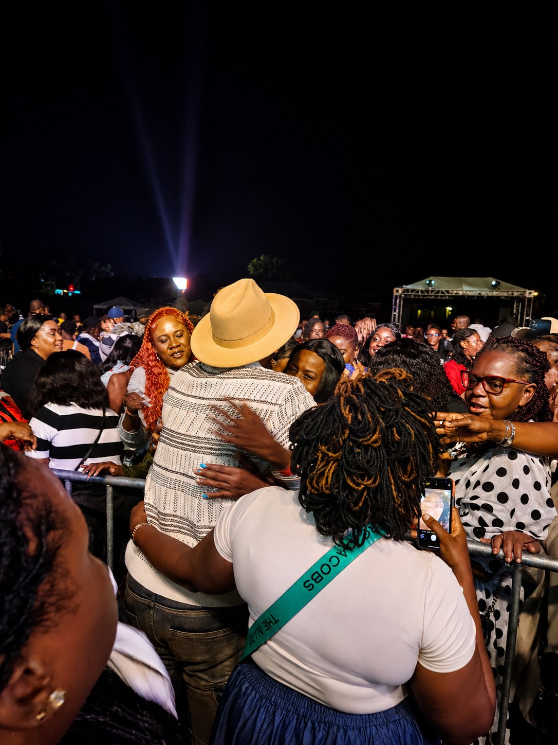 Kevin Downswell down among the audience at a night event, embracing people at the barrier as a stage glows behind