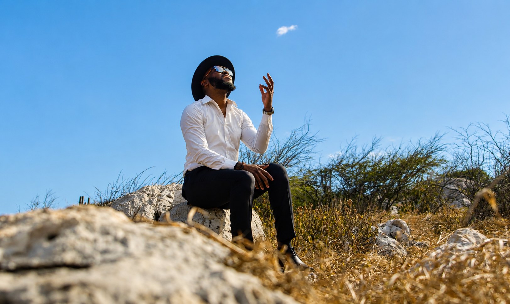 Kevin Downswell seated on a hillside beneath an open sky, looking upward